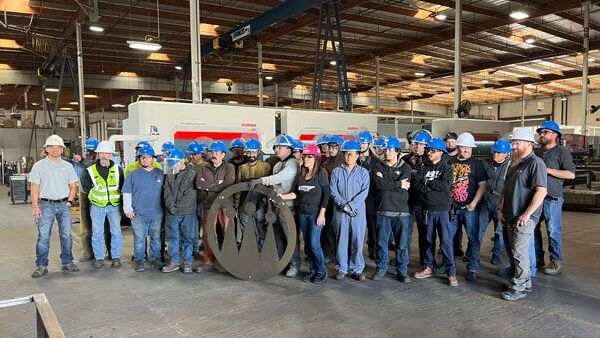 Crown employees standing on shop floor behind the Crown logo